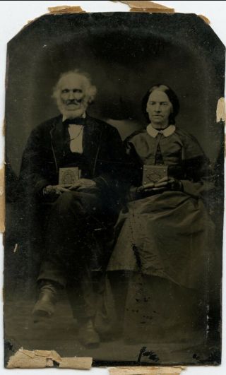 Tintype Of An Old Man And Woman Holding Albums.