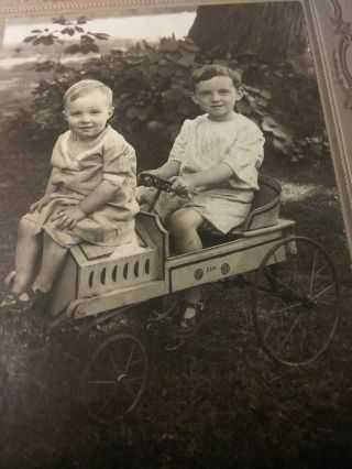 Two Children Riding On A Very Early 20th Century Pedal Car