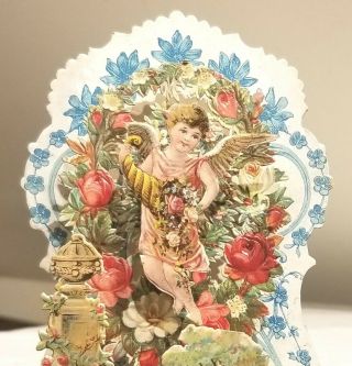 Cupid hovering over Victorian Flower Garden.  3 - dimensional Card.  Early 1900s. 2